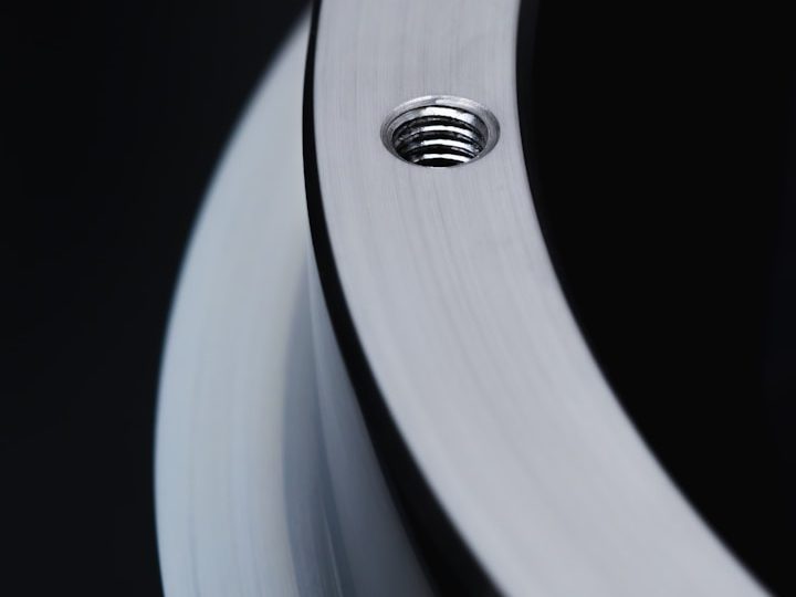 Close-up of a metal edge with threads and black background.